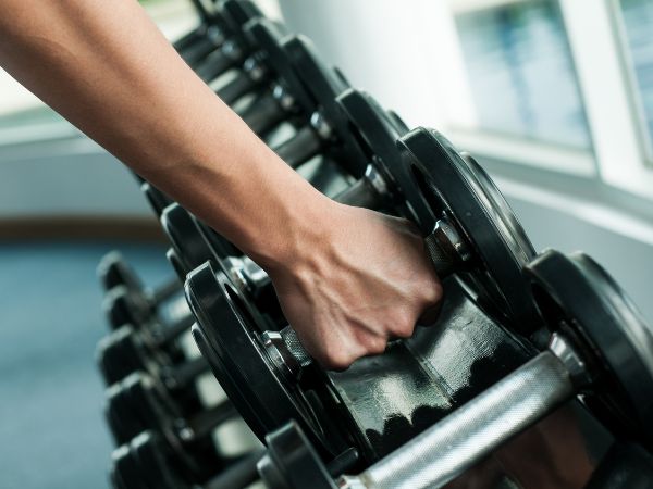 pessoa segurando halter em sala de musculação