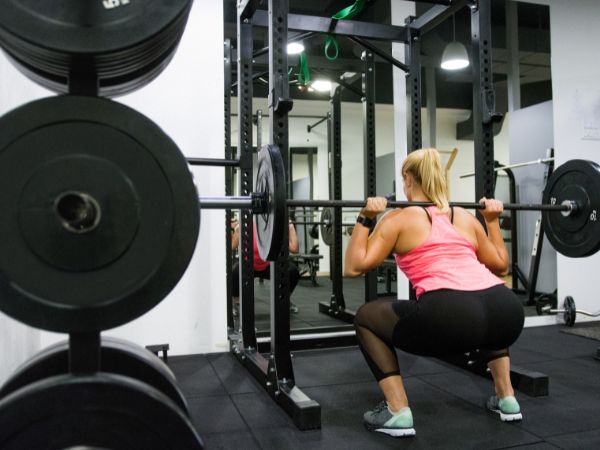 Mulher realizando agachamento livre em uma academia