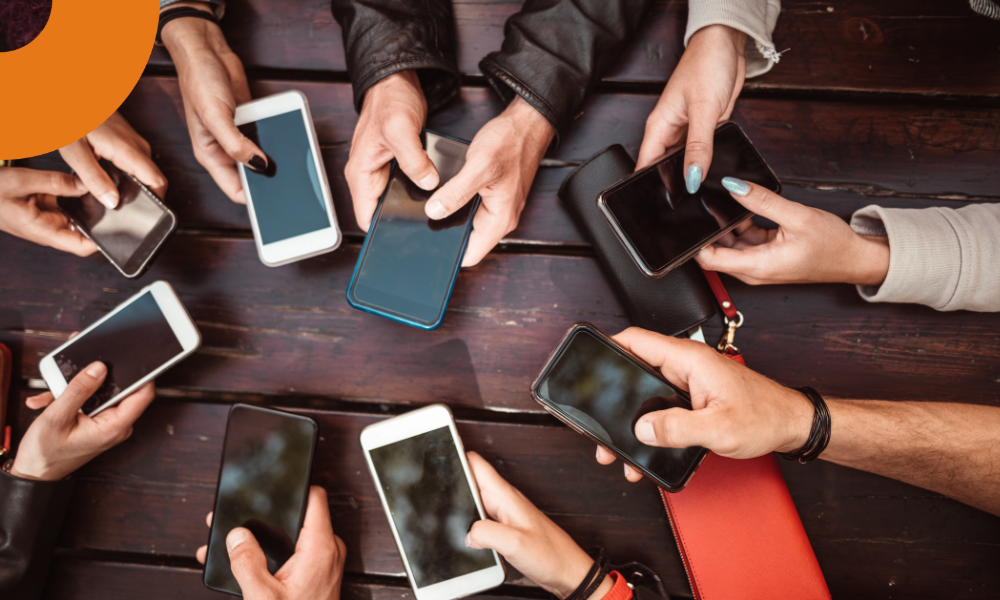 diversas pessoas com smartphones no centro da mesa.